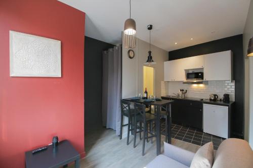 Il comprend une cuisine et un salon avec un mur rouge. dans l'établissement Le Zen, T2 chic et cosy, wifi par SOVALFI, à Saint-Étienne