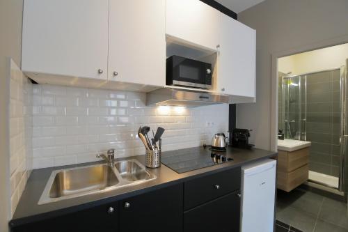 une cuisine avec un évier et un micro-ondes dans l'établissement Le Zen, T2 chic et cosy, wifi par SOVALFI, à Saint-Étienne