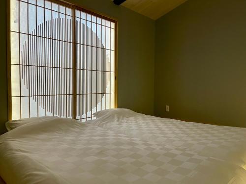 a bedroom with a bed and a large window at TABITABI KANOE ROKU in Kyoto