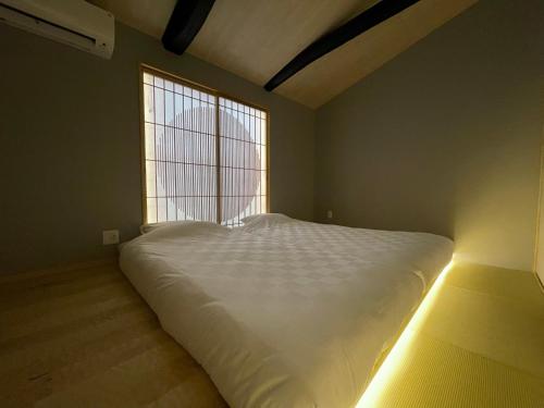 a large white bed in a room with a window at TABITABI KANOE ROKU in Kyoto