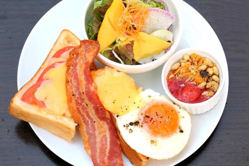 a plate of breakfast food with eggs bacon and a salad at Via Inn Kanazawa in Kanazawa