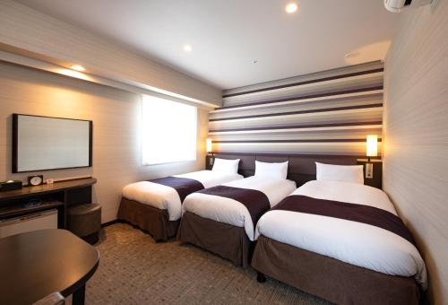 a hotel room with two beds and a television at Via Inn Kanazawa in Kanazawa