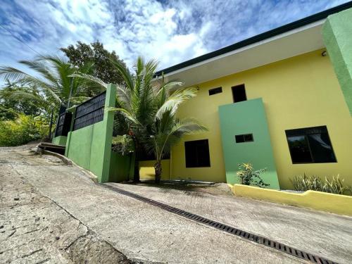 a yellow and green building with a palm tree next to it at Yellow House in Quepos