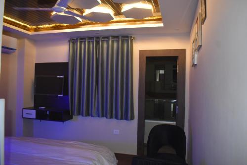 a bedroom with a bed and a window with a curtain at Hotel Lilac Doors in Patna