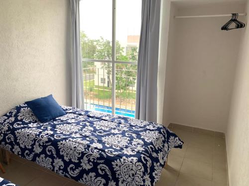 a bedroom with a blue and white bed and a window at Departamento 2 habitaciones vista a la alberca Sky by EITA in Cancún