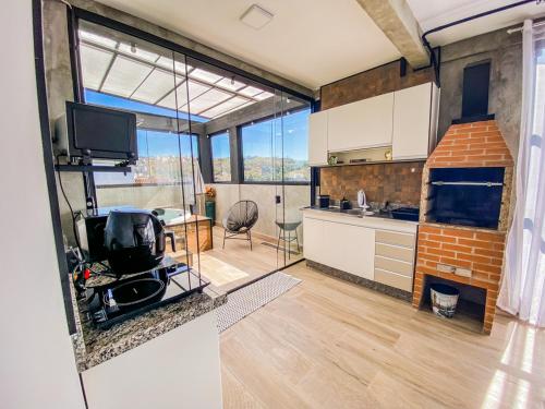 a kitchen with a large window and a living room at Uai House com jacuzzi, teto rooftop retrátil e colchão massageador in Poços de Caldas