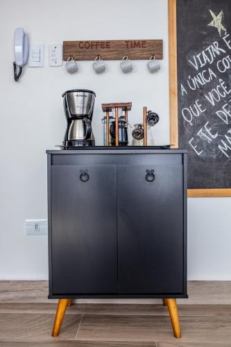 a black cabinet with a coffee maker on top at Uai House com jacuzzi, teto rooftop retrátil e colchão massageador in Poços de Caldas