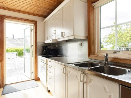 cocina con armarios blancos, fregadero y ventana en Holiday home Svendborg XIII, en Svendborg