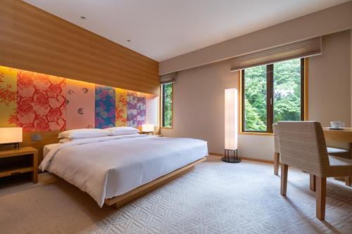 um quarto com uma grande cama branca e uma secretária em Hyatt Regency Kyoto em Quioto