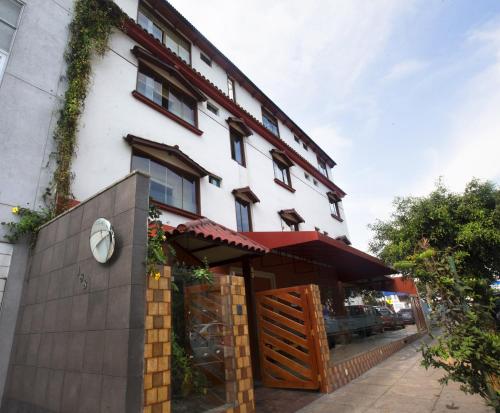 a white building with a wooden door and a fence at Hotel Tinkus Inn in Lima