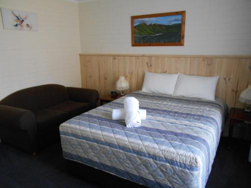 a bedroom with a bed with a chair and a teddy bear on it at Grampians View Cottages and Units in Halls Gap
