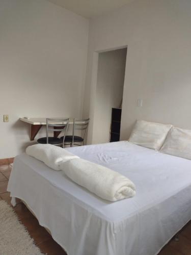 a bedroom with a white bed with two towels on it at Pousada Recanto Alaketu Hospedagens in Campo Grande