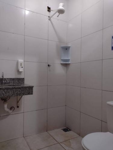 a white tiled bathroom with a toilet and a shower at Pousada Recanto Alaketu Hospedagens in Campo Grande