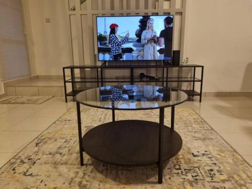 Modern 4BR Double Storey @ Setia Alam في شاه عالم: غرفة معيشة مع طاولة زجاجية وتلفزيون