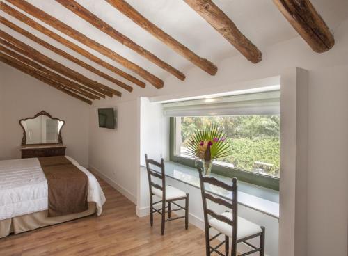 a bedroom with a bed and two chairs and a window at Jardines de Casablanca in Caravaca de la Cruz