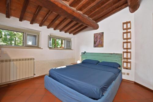 a bedroom with a blue bed in a room with windows at Casa Guna in Asciano