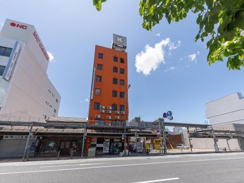 a tall orange building on the side of a street at Tabist Business Hotel Kanazono Gifu in Gifu