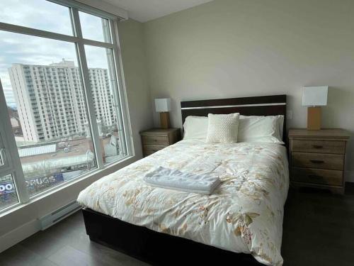 a bedroom with a large bed with a large window at Luxury downtown 2 bedroom suite with Ocean views in Victoria