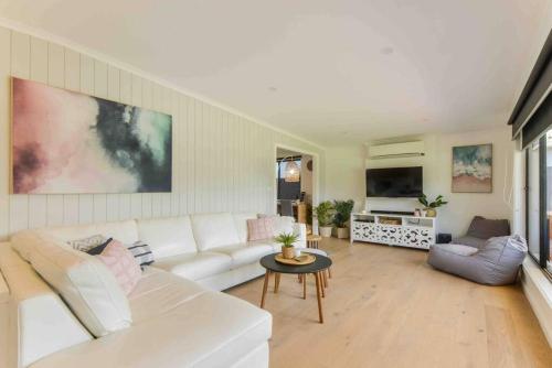 a living room with a white couch and a tv at Foam St Serenity in Rosebud