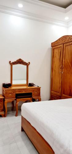 a bedroom with a bed and a dresser and a mirror at Khách sạn Le Royal in Lien Nghiia