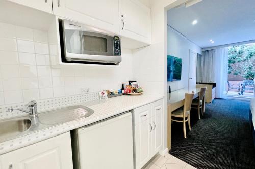 a kitchen with a sink and a microwave at Coogee Sands Hotel & Apartments in Sydney