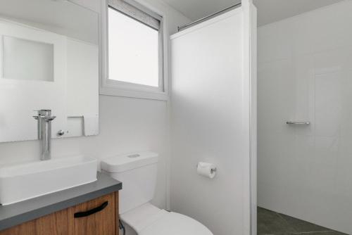 a bathroom with a toilet and a sink and a window at Boomerang Hotel in Mackay
