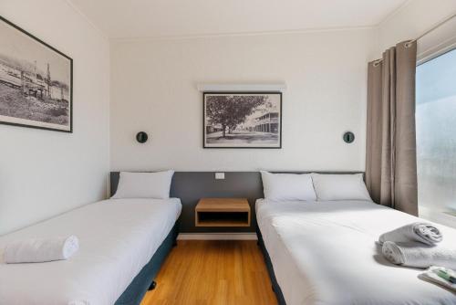2 Betten in einem Zimmer mit einem Tisch dazwischen in der Unterkunft Boomerang Hotel in Mackay