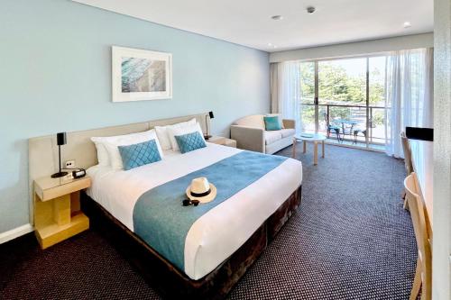 a bedroom with a large bed with a hat on it at Coogee Sands Hotel & Apartments in Sydney