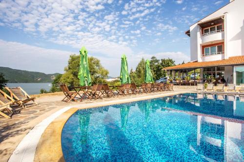 a swimming pool with chairs and umbrellas next to a building at Family Hotel Saint Konstantin in Glavatartsi