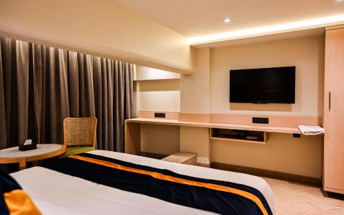 a hotel room with two beds and a flat screen tv at Suvidha Suites in Vasai