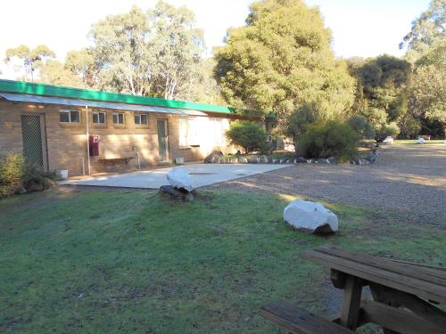 a building with a picnic table and rocks in the grass at Grampians View Cottages and Units in Halls Gap