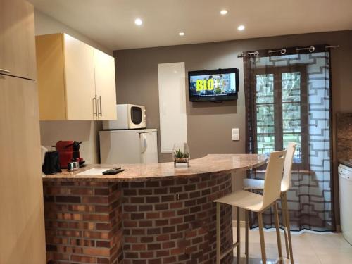 a kitchen with a brick counter with a tv on the wall at Studio belles prestations en Cévennes in Chamborigaud