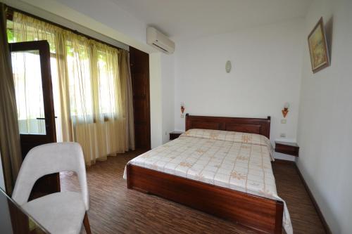 a bedroom with a bed and a chair and a window at More Family Hotel in Sozopol