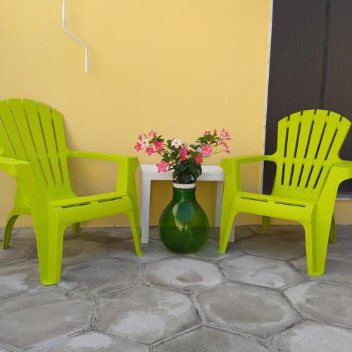 twee groene stoelen en een tafel met een vaas met bloemen bij La casetta con cortile in Lecce