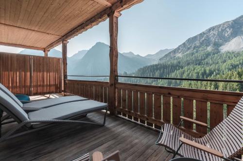 a porch with two chairs and a view of mountains at Hotel Alpensonne - Panoramazimmer & Restaurant in Arosa