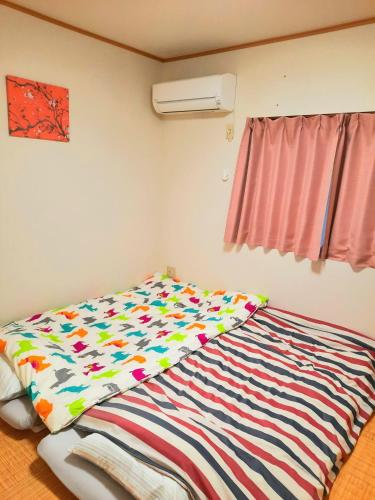 1 dormitorio con 1 cama con un edredón colorido en 一棟丸ごと・YOURSとなり en Osaka