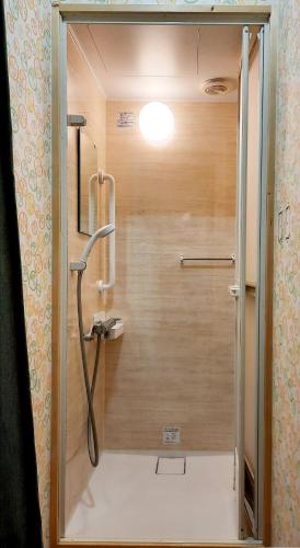 a shower in a bathroom with a wooden wall at 一棟丸ごと・YOURSとなり in Osaka