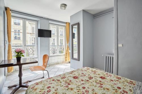 um quarto com uma cama, uma secretária e janelas em Le Petit Borda em Paris