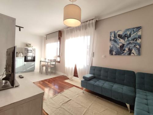 uma sala de estar com um sofá azul e uma televisão em Acogedor apartamento junto a la Plaza em Villasana de Mena
