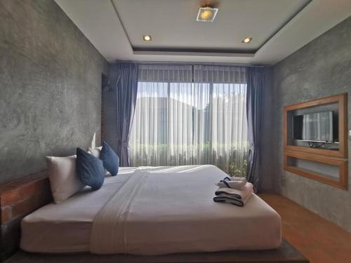 a bedroom with a large bed with a large window at BaanMee Phuket SHA Plus in Chalong 