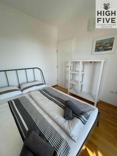 a large bed in a white room with a chair at Apartment High Five Novalja in Novalja