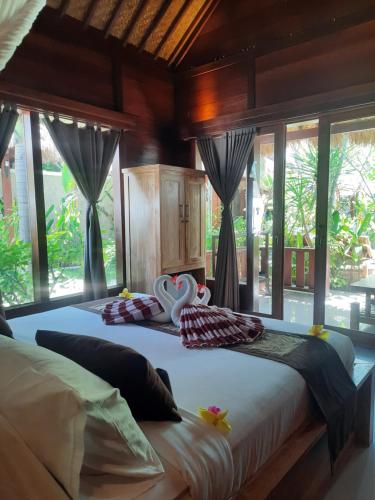 two beds in a room with large windows at Molah Gili Villa in Gili Air