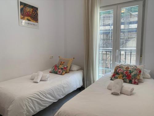 マラガにあるHomely Málaga Atarazanasの窓付きの客室で、白いベッド2台が備わります。
