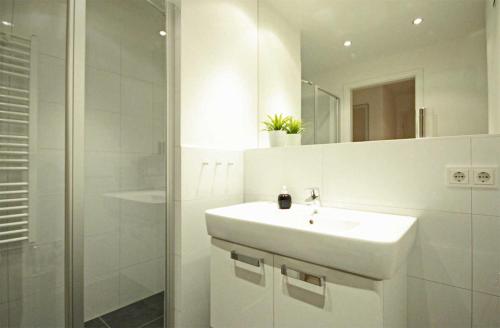 a white bathroom with a sink and a shower at Haus Meeresblick - Ferienwohnung Auszeit (Ref. 136764) in Baabe