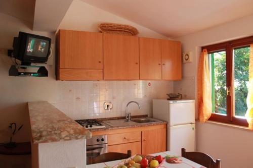 a kitchen with wooden cabinets and a table with a television at Fewo Sole e Azzurro in Capoliveri