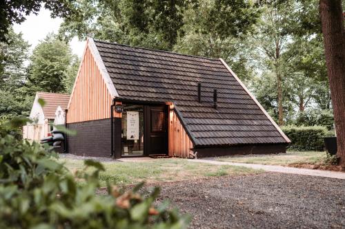 a small red barn with a black roof at Het Houten Huisje 84 Luxe vakantiewoning Zuid Limburg in Simpelveld