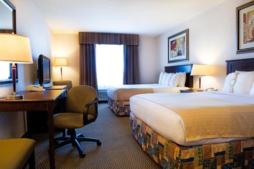 a hotel room with two beds and a desk at Holiday Inn Hotel & Suites-West Edmonton by IHG in Edmonton