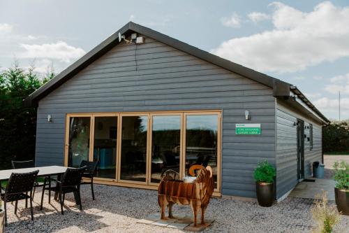 a large gray building with a table and chairs at King Richard's Luxury Lodge - Sleeps up to 8, Dog Friendly, Near Sherwood Forest at Fairview Farm in Nottingham set in 88 acres and great for Groups, Family Gatherings & Corporate events in Nottingham
