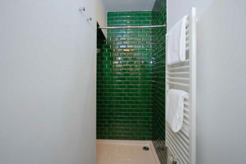 a bathroom with a green tiled shower with a tub at Domaine de Ronchinne - Château et Ecuries in Maillen