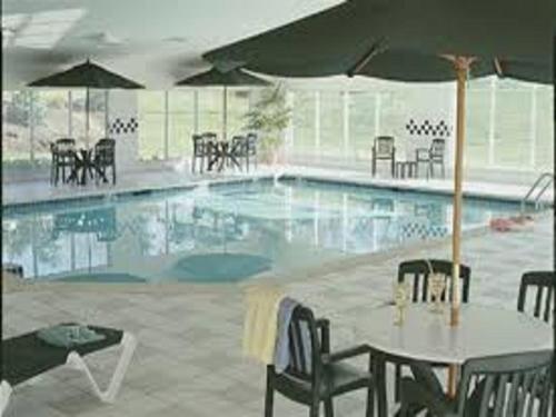 uma piscina com uma mesa e cadeiras e um guarda-sol em Country Inn & Suites by Radisson, Lancaster Amish Country , PA em Lancaster